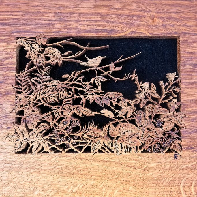 Ornamental cut-out design featuring birds and foliage on a wooden background.