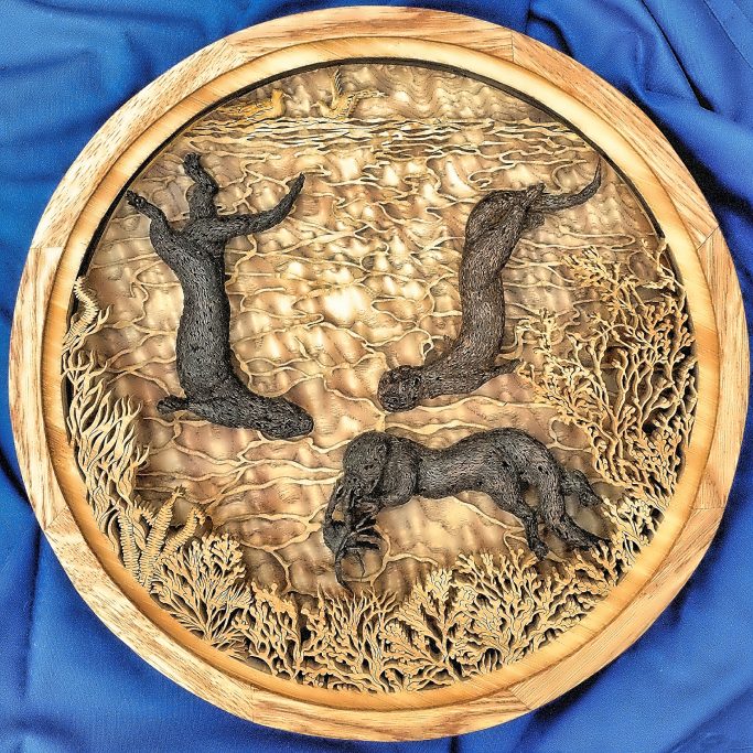 Wooden relief artwork featuring otters amid intricate underwater foliage.