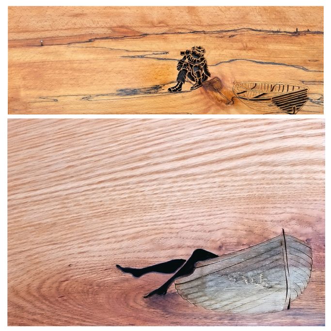Wooden artwork featuring a figure sitting and a boat in water.