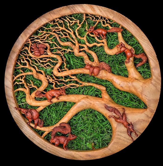 Wooden relief artwork of a tree with squirrels.