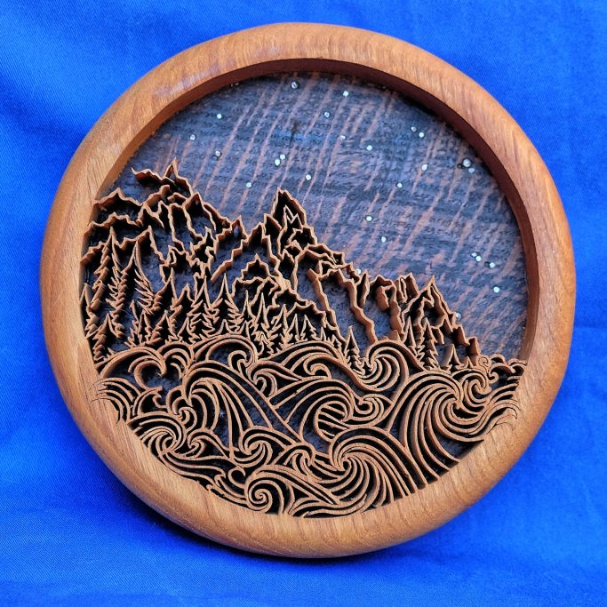 Abstract hand pierced wooden roundel sea, mountains and a starry sky