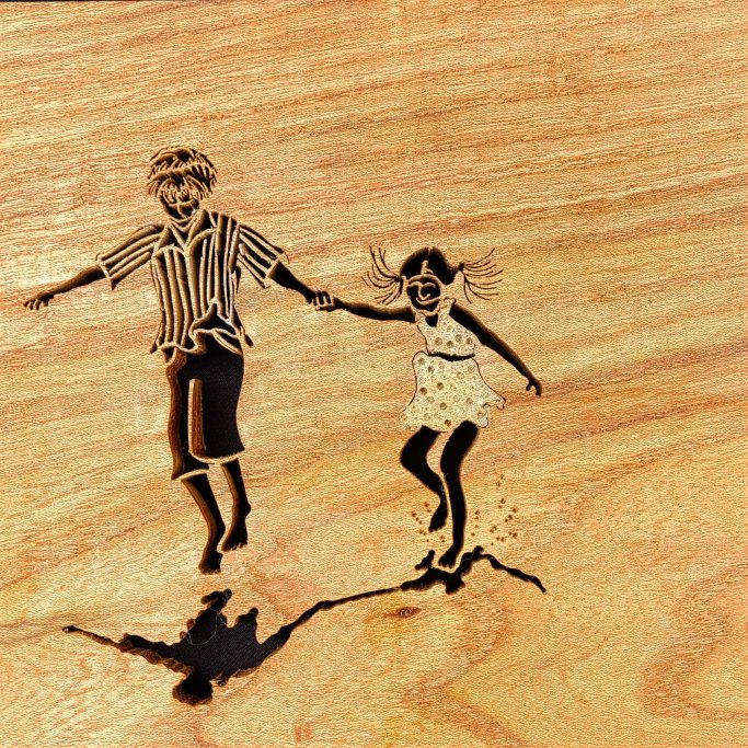A boy and girl joyfully running together on a wooden surface.
