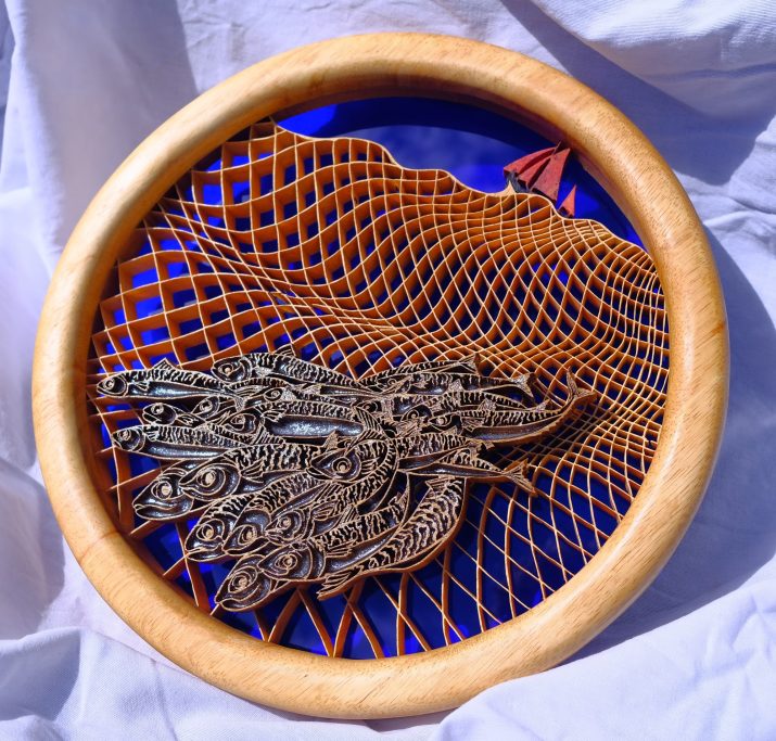 A wooden hoop with intricate netting, school of fish and a sail boat
