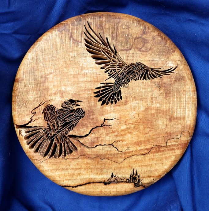 Two Ravens cut in silhouette on a moon like circle of wood