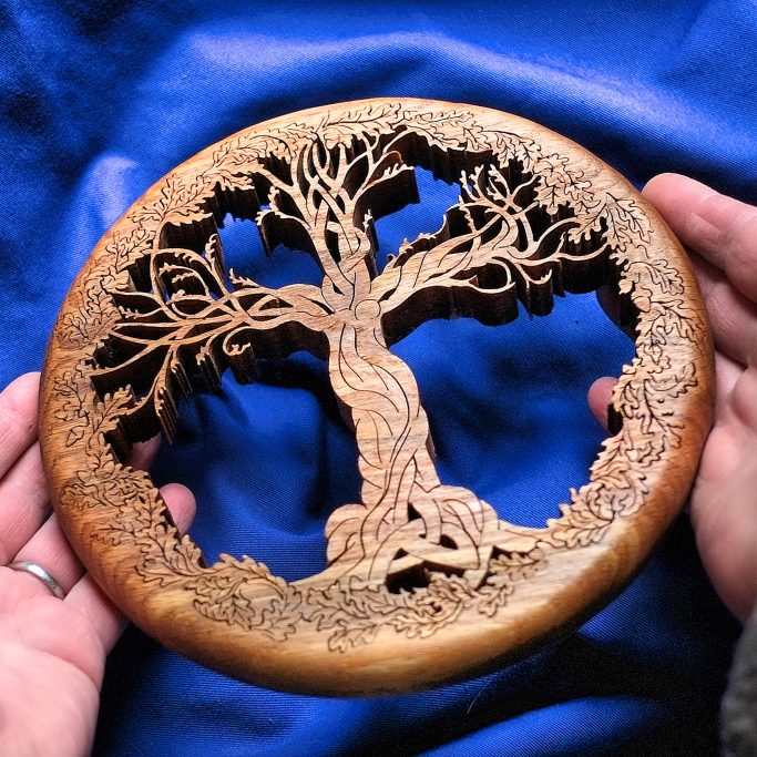 Intricate hand cut wooden roundel featuring a stylised cruciform tree and Jesus form