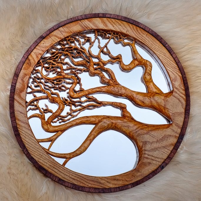 Wooden circular mirror framed with an intricate tree design.