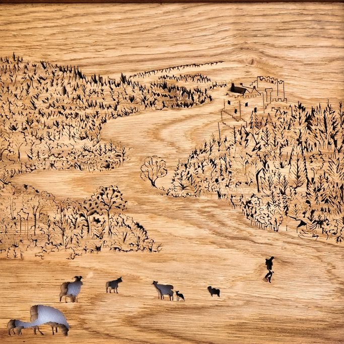A decorated wooden panel depicting a landscape with trees and grazing sheep.