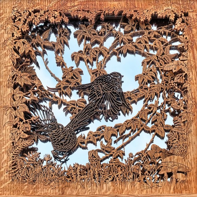 Intricate wood carving of birds flying through branches surrounded by foliage.